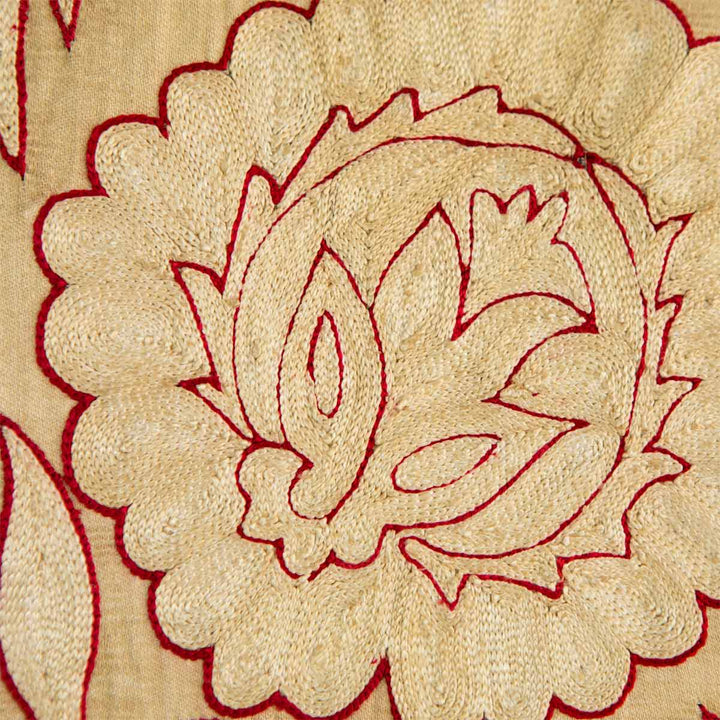 Detailed view of Mekhann's cream botanical throw, showing how the red thread details contrast with the like cream embroidered, working together to make up this beautiful floral design motif. 