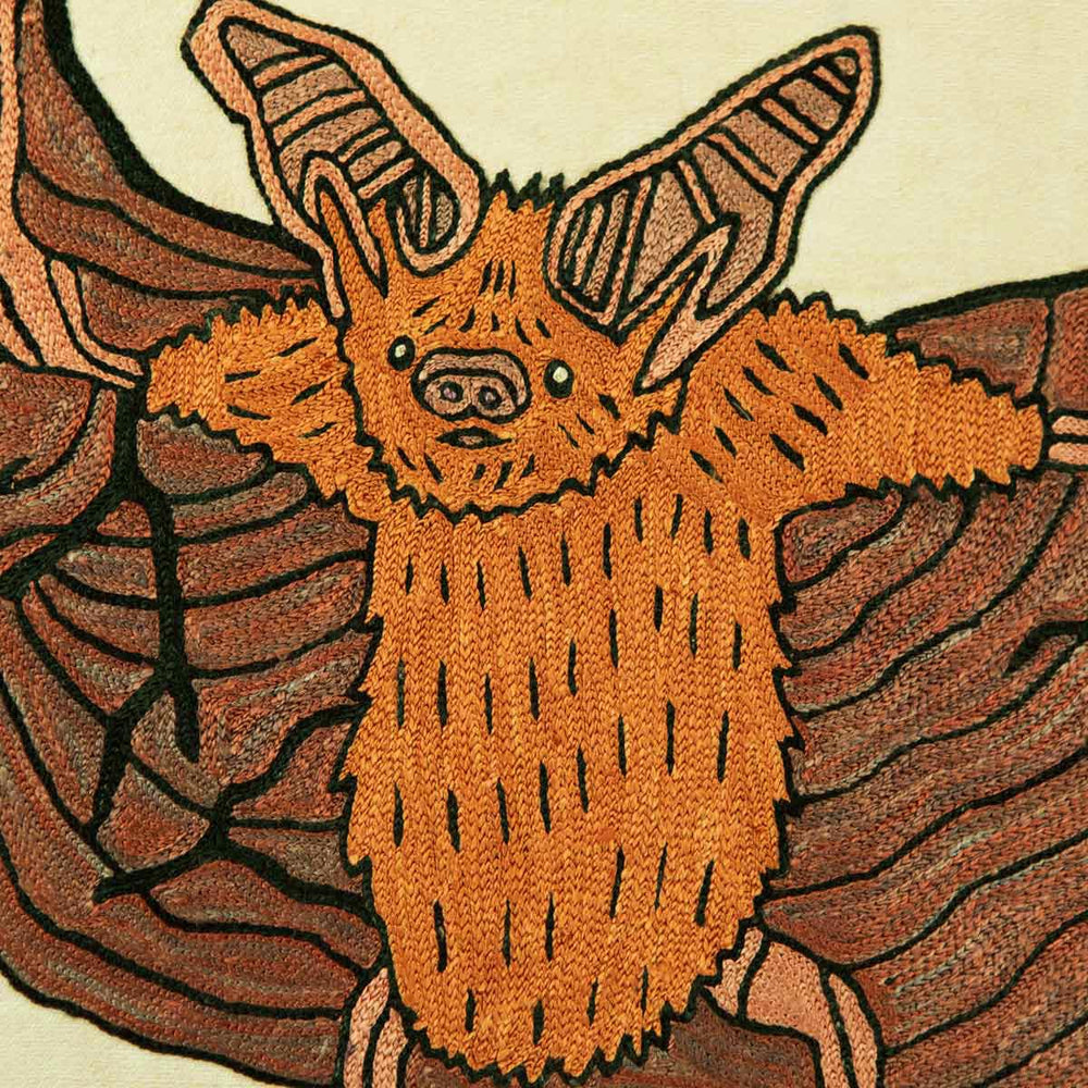 Close up of Mekhann's cream silk hand embroidered bat artwork, giving a more detailed look at the face of the bat, all of the details of the body have been outline in black to give more definition to the features of the hand embroidered bat. 