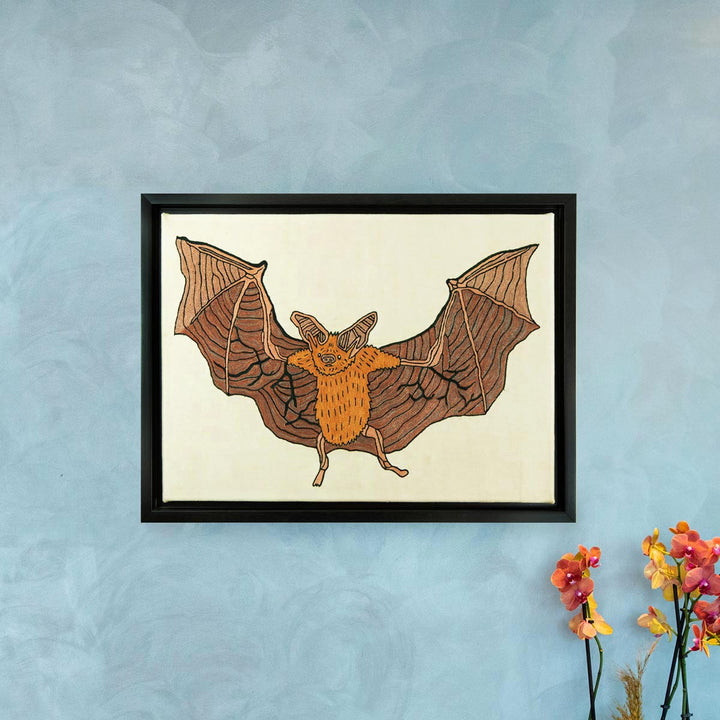 In use view of Mekhann's cream silk hand embroidered bat artwork, showing the artwork hung on a wall to give a better idea to the view about the size of the frame.