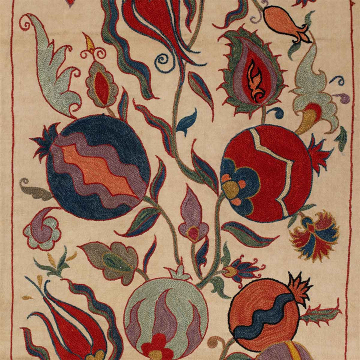 Close up of motifs view of Mekhann's cream ottoman vines runner, showing some of the embroidered vine patterns in the runner in a bright arrangement of colours.