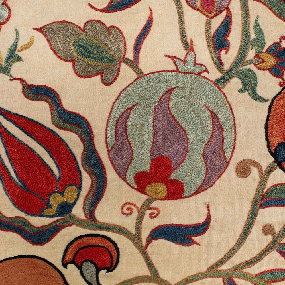 Details of Mekhann's cream ottoman vines runner, showing the detail of a light blue pomegranate motif, hand embroidered in light blue onto a canvas of cream coloured silk.