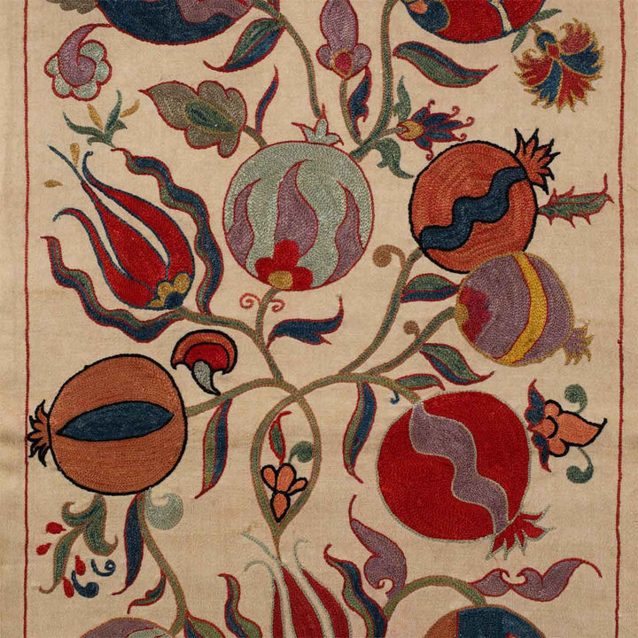 Close up view of Mekhann's cream ottoman vines runner, showing a collection of motifs in bright colours, including pomegranates, vines and tulips.