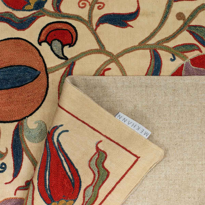 Folded view of Mekhann's cream ottoman vines runner, showing the beige colour of the back linen of the runner with the Mekhann label attached.