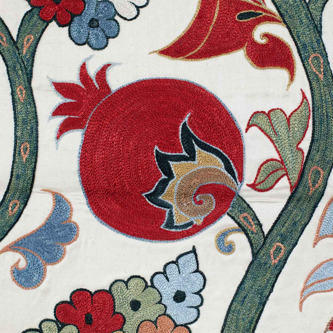 Detailed view of Mekhann's cream ottoman vines runner, showing the embroidered pomegranate and patterns up close in reds and greens against the cream silk background.