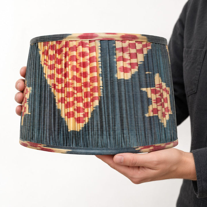 Echo Pewter silk ikat lampshade in Medium held in two hands, showing its pleated construction and pattern at scale.