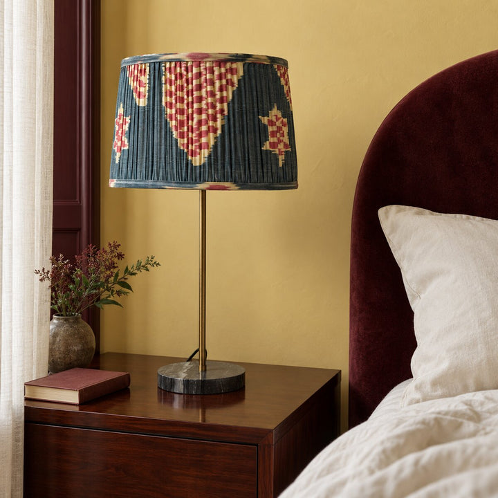 Echo Pewter silk ikat lampshade in Medium shown unlit on a bedside lamp in natural daylight.