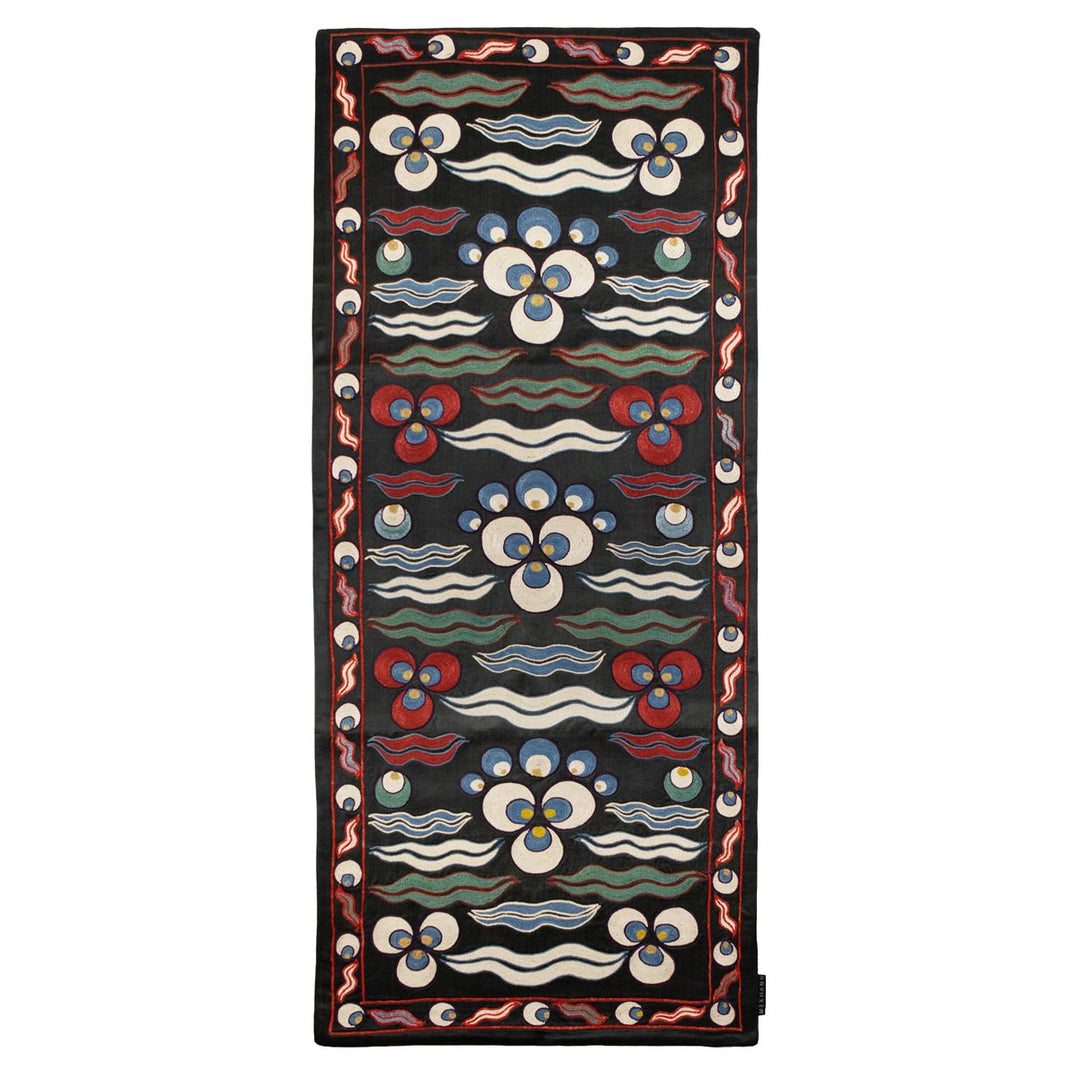 Front view of Mekhann's black cintamani runner, showing a display hand embroidered silk cintamani patterns on a black silk base with a multitude of patterns in colours blue, red, and white.
