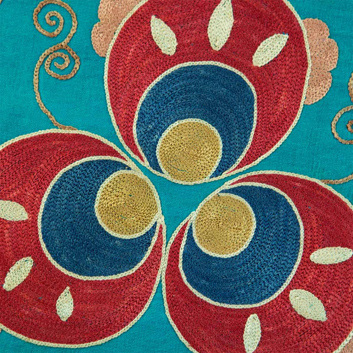 Close up view of Mekhann's floral turquoise silk embroidered artwork, focusing on the red, blue and yellow motif, which bring the intricate stitches and textures to life.
