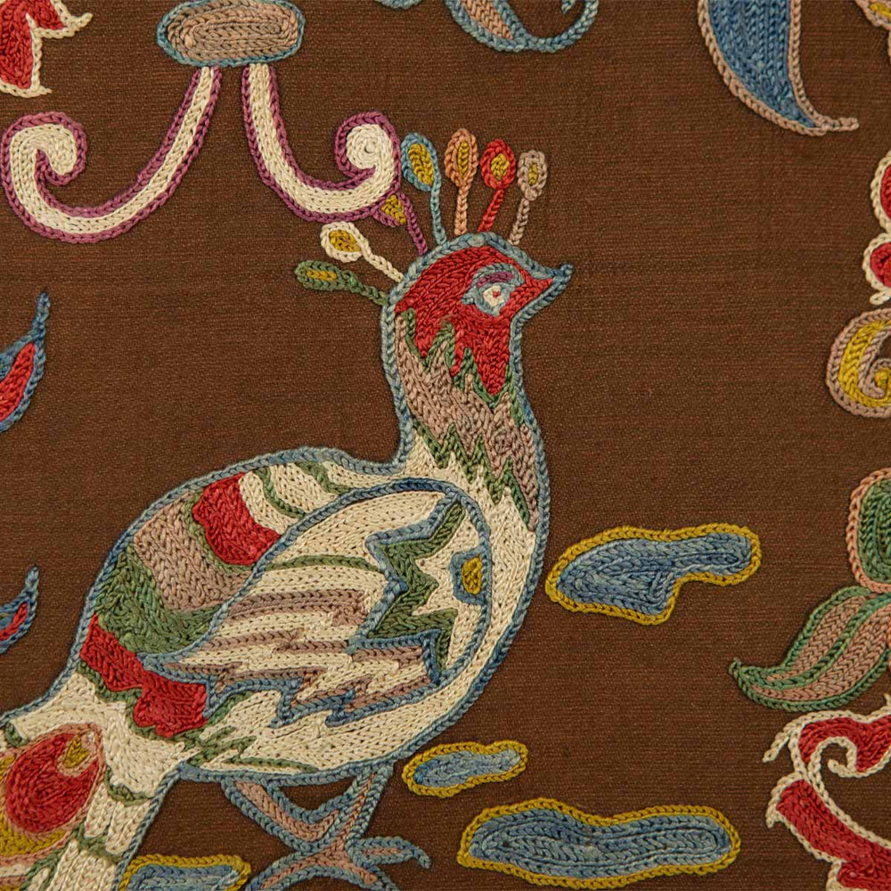 Close up view of Mekhann's brown silk peacock artwork, where we can see the upper part of the peacock in red, blue, cream, green and yellow, all on a base of brown coloured silk.