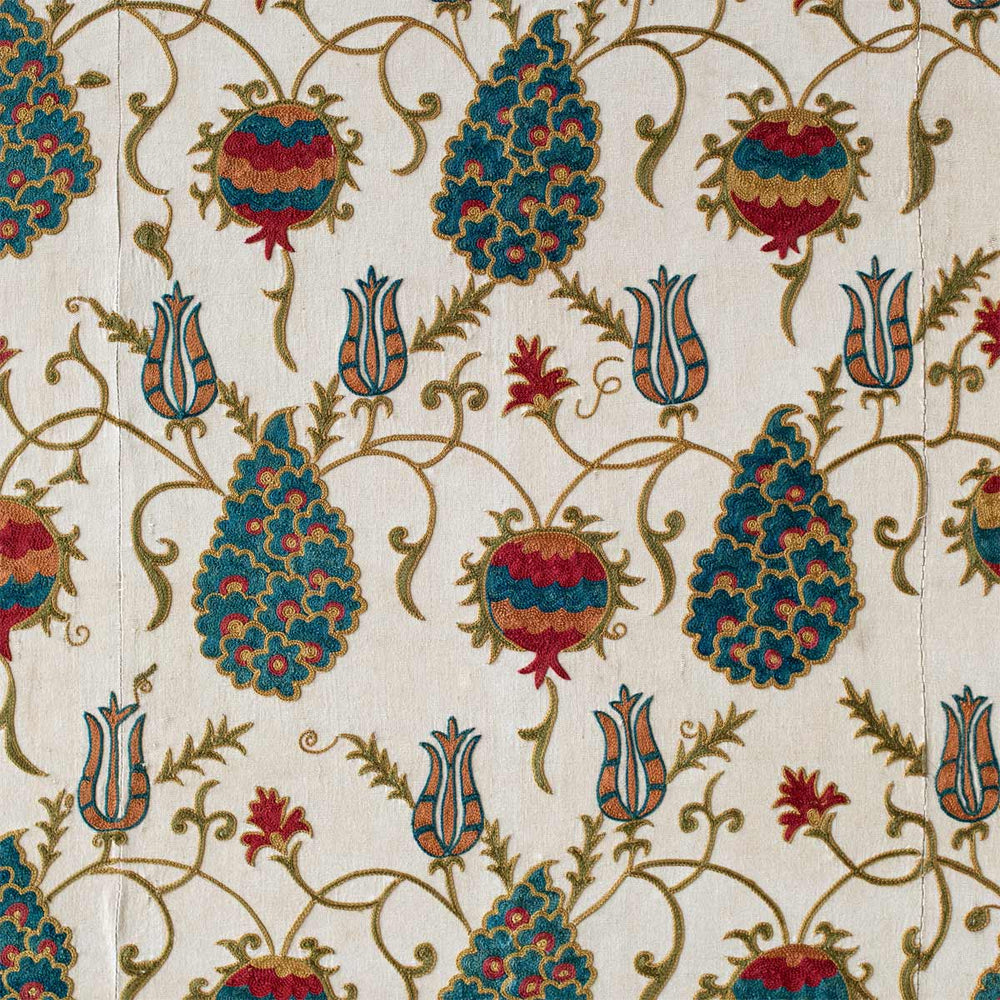 Close up view of Mekhann's cream silk grape vines artwork, detailing the grapevines patterns in a dark yellow tone, surrounded by tulips and multicoloured pomegranates, all hand embroidered onto a cream silk base.