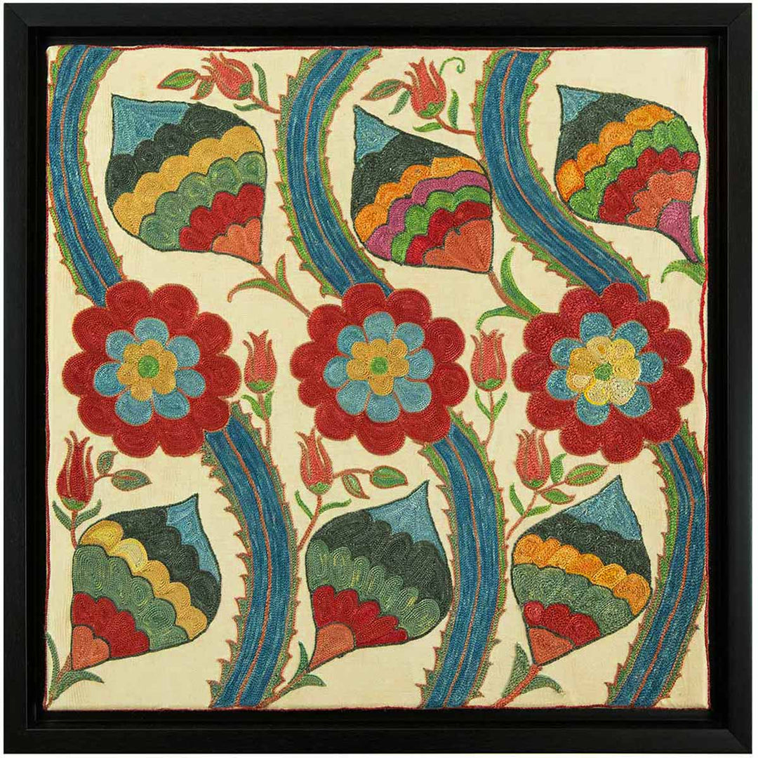Front view of Mekhann's cream silk vines artwork, featuring a silk cream base with a design of curving vines and stylised flowers in rich reds, blues, and greens, all bordered and framed within a black coloured frame.
