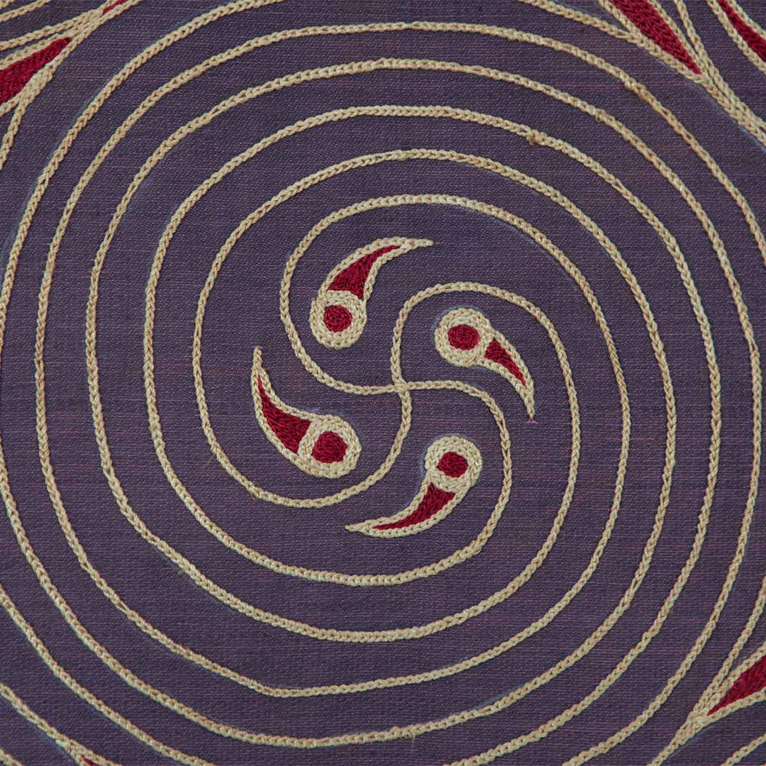 Close up view of Mekhann's dark purple and red silk embroidered spirals artwork, focusing on the complex centre of the swirl embroidery in cream and red embroidery on dark purple silk.
