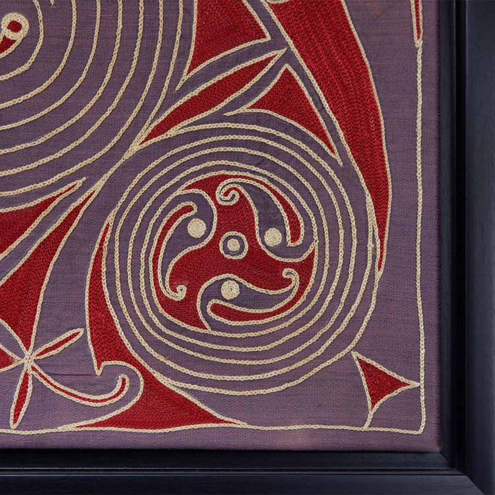 Corner view of Mekhann's dark purple and red silk embroidered spirals artwork, A corner close-up of Mekhann's dark purple silk embroidery, highlighting attention to detail of cream and red swirl embroidery that contrasts purple silk background