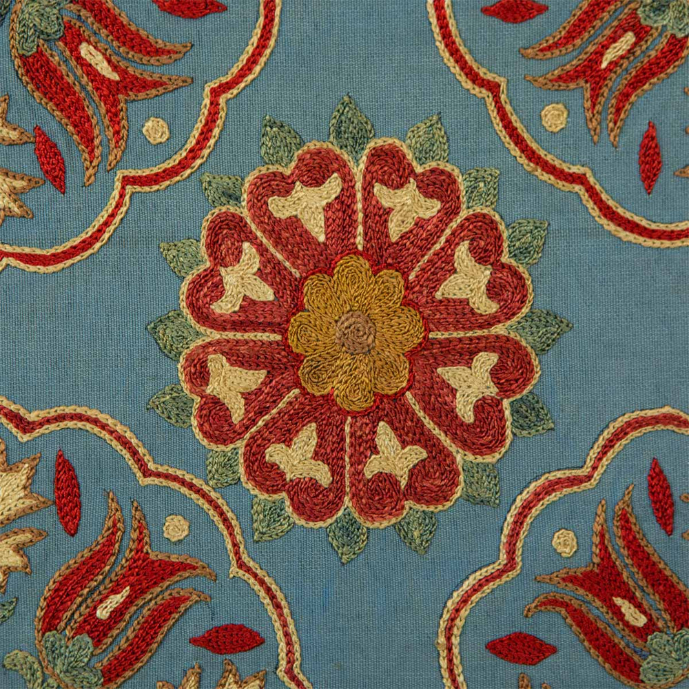 Close up view of Mekhann's grey hand embroidered silk spirals artwork, focused on a centre flower motif in red, cream, and yellow embroidered silk.