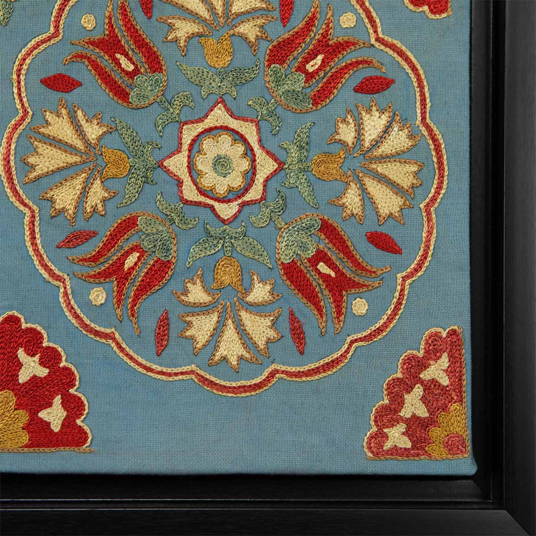 Corner view of Mekhann's grey hand embroidered silk spirals artwork, showing the red, yellow and cream embroidered details in the corner of the frame.