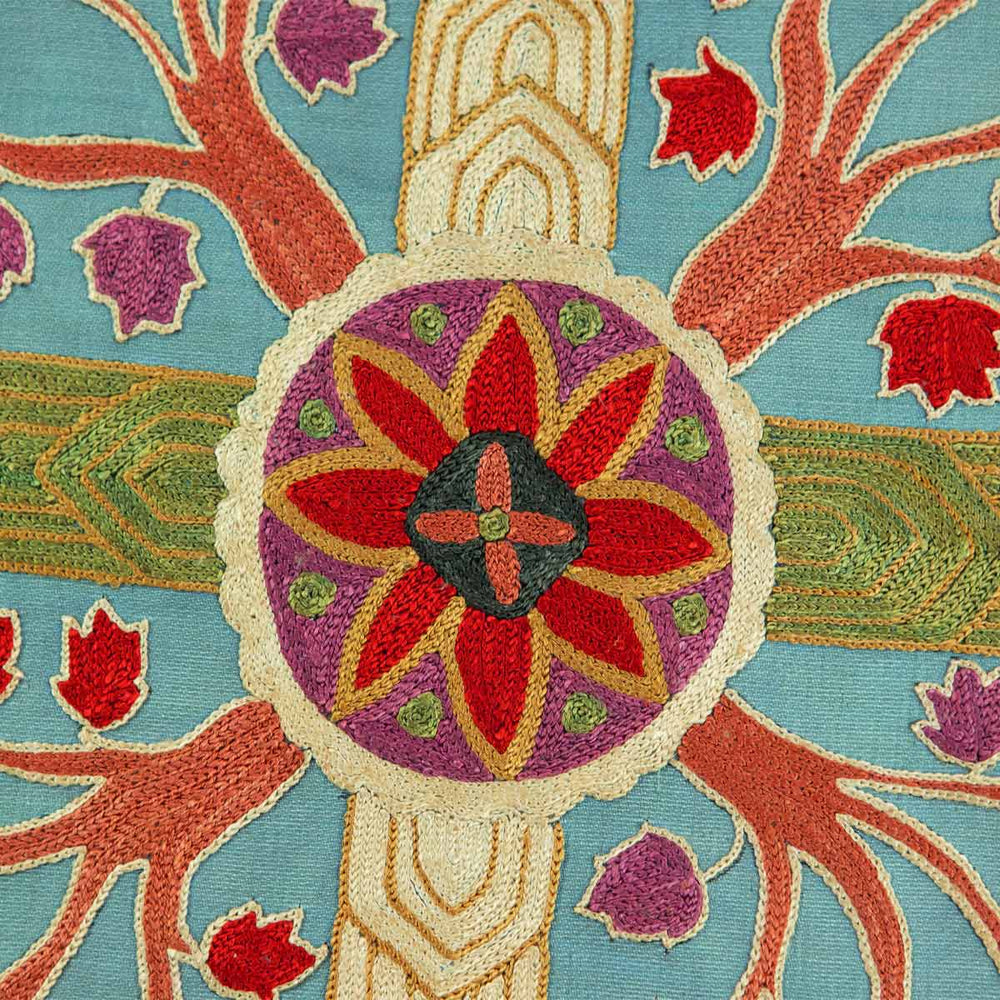 Close up view of Mekhann's grey tree of life silk embroidered artwork, focusing on the central medallion and the surrounding botanicals, highlighting the contrast of colours and the texture of the embroidery stitches.