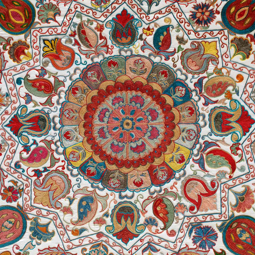 Centre medallion view of cream silk, multicoloured embroidered framed artwork, showing the details  of the central medallion and all of the flowers surrounding it in red, blue, green, teal and light yellow tones.