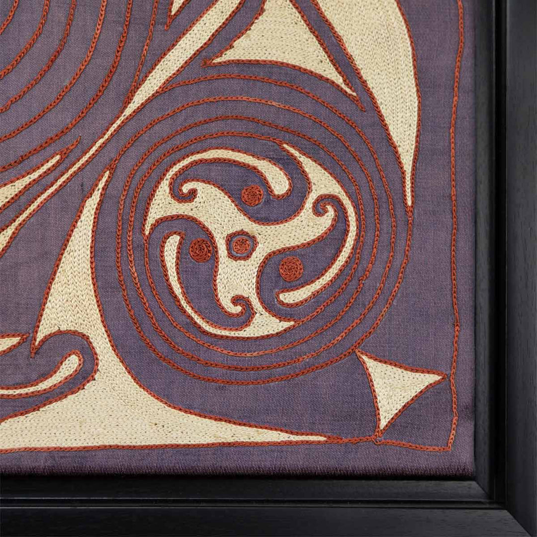Corner view of Mekhann's purple silk embroidered spirals artwork, showing a corner swirl pattern, with the black frame in view.
