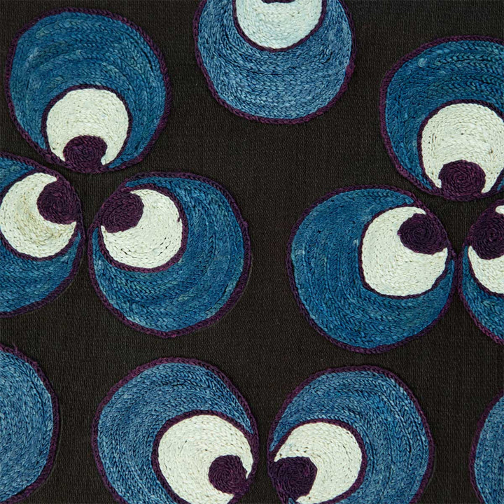 Close up view of Mekhann's hand embroidered black silk cintamani artwork, revealing a dark purple outline of the blue and white Cintamani patterns.