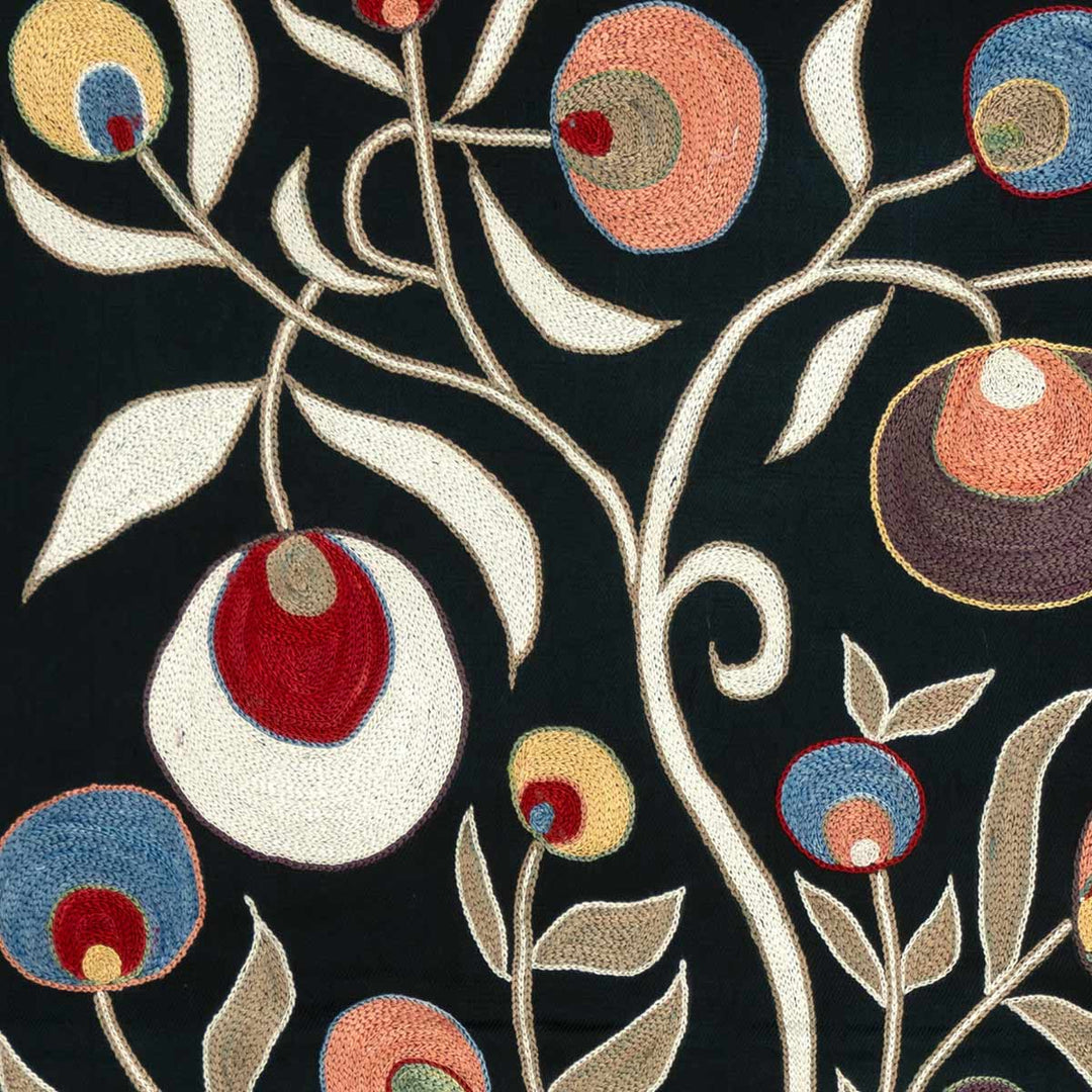Details view of Mekhann's black pomegranate silk artwork, focusing on the vibrant pomegranate and vine patterns, the interplay of colour revealing the artwork's detailed artistry.