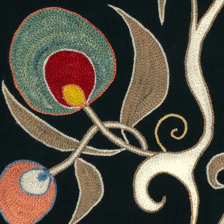 Detailed view of Mekhann's black pomegranate silk artwork, showing up close one of the embroidered silk motifs in blue with the cream vines.