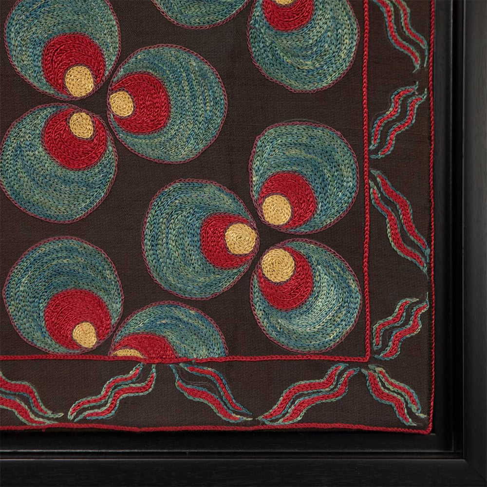 Corner view of Mekhann's black silk, with red and blue cintamani patterns hand embroidered artwork. Showing the black frames corner and where the art work ends and the frame begins.