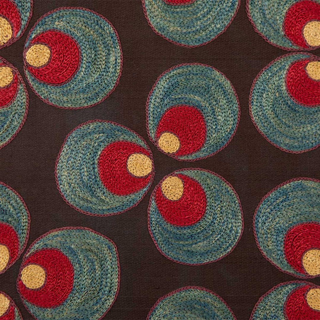 Close up view of Mekhann's black silk, with red and blue cintamani patterns artwork, showing the hand embroidered Cintamani circle patterns in red, light yellow, and blue, all set against a black silk background.