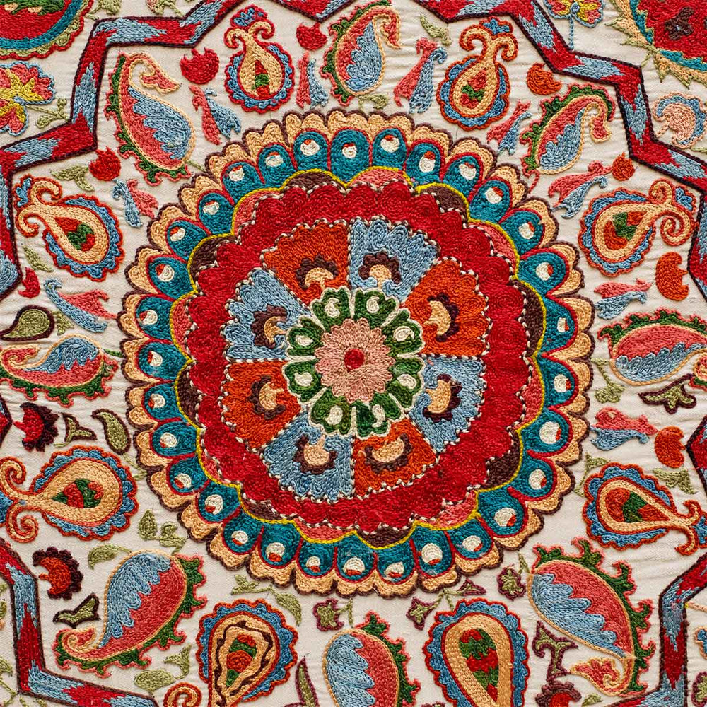 Centre view of Mekhann's cream and multicoloured silk artwork with a collection of hand embroidered patterns. Revealing in detail the red centre medallion, surrounded in natural floral shapes in shades of blue, red, green, light yellow, with a dark brown outlining.