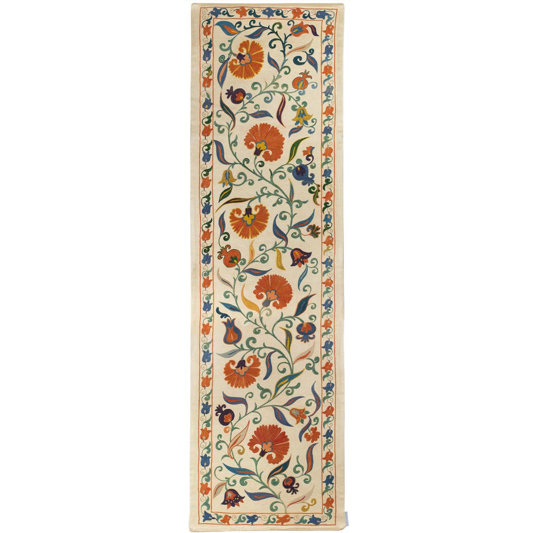 Front view of Mekhann's cream ottoman vines runner, displaying a vibrant collection of tulips and orange carnation motifs set against a base of cream silk allowing the embroidered patterns to stand out.