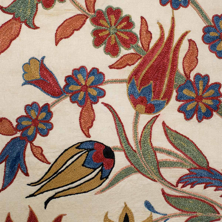 Detailed view of Mekhann's cream iznik throw, showing two tulip motifs in a beautiful collection of blues, reds, greens, and light oranges.