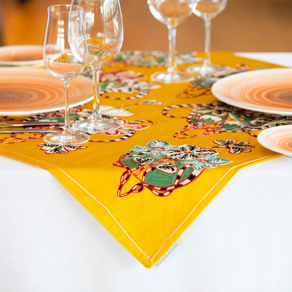 In use image of Mekhann's baroque yellow petite throw, showing the throw on top of a table is a dinning setting, giving ideas of where and how the silk throw can be used.