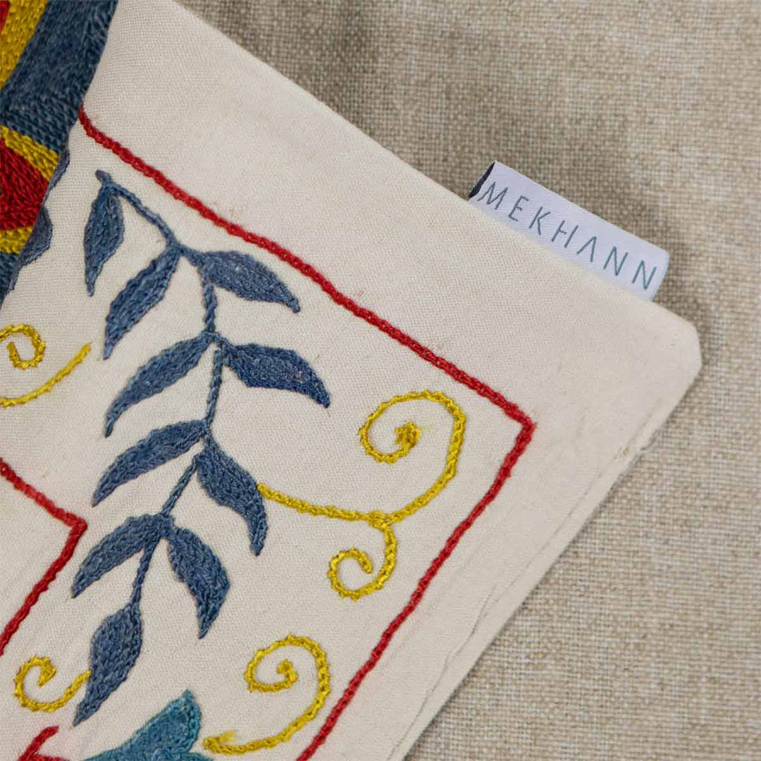 An alternative folded view of Mekhann's cream iznik petite throw, showing the Mekhann label against the back lining fabric.