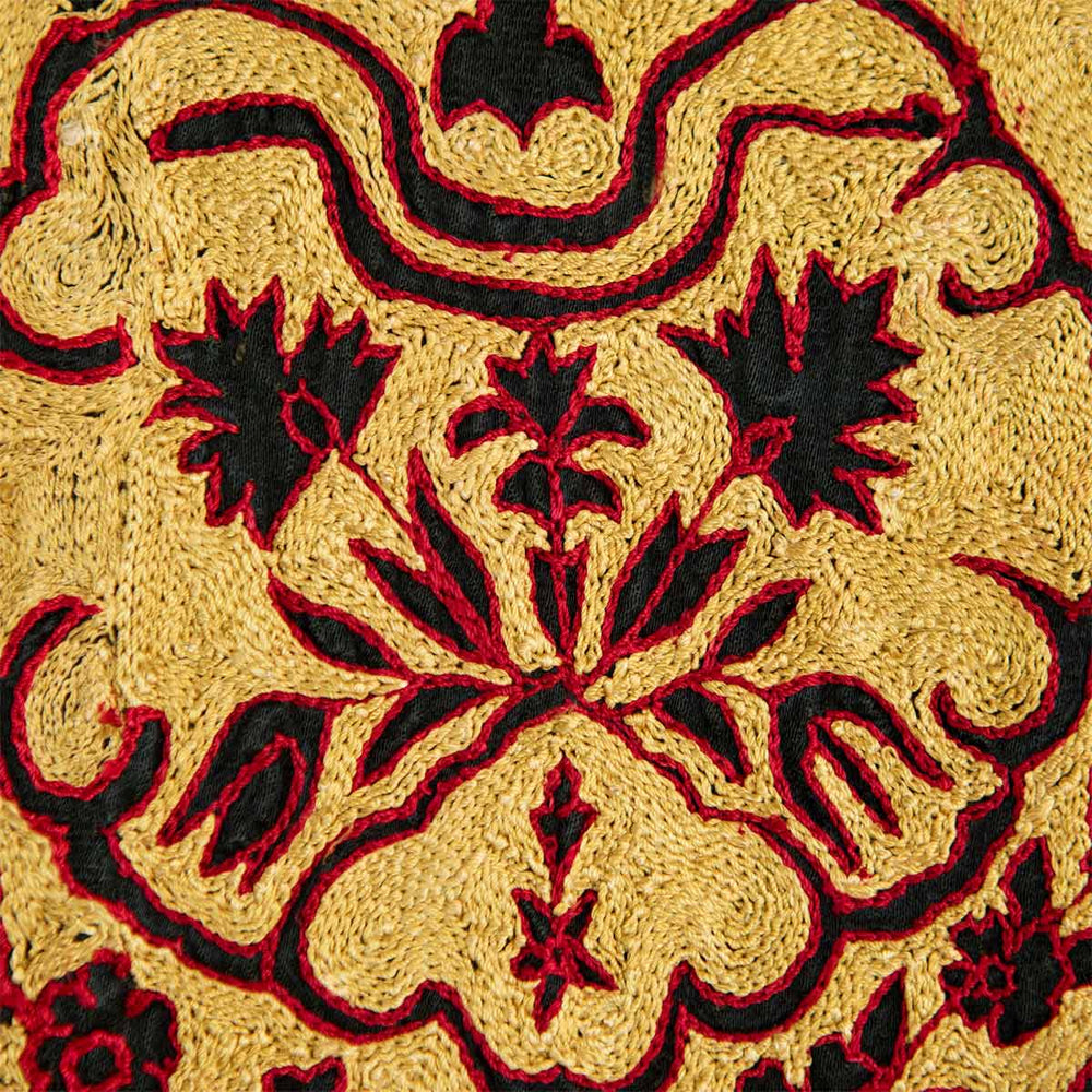 Close up view of Mekhann's black arabesque throw, showing how the hand embroidered red and cream threads come together around the black negative space to create and form the arabesque patterns.