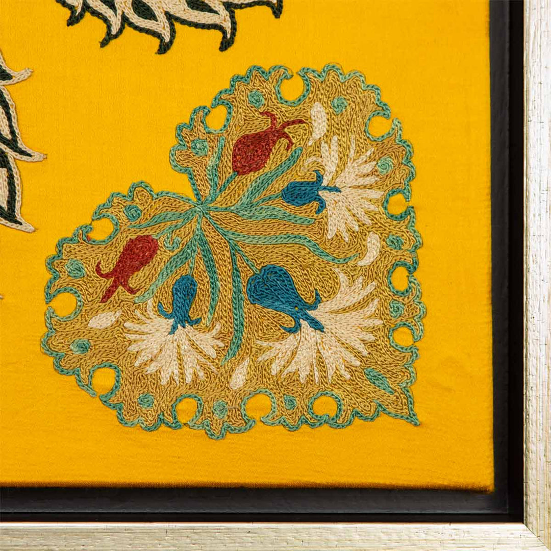 Corner view of Mekhann's yellow botanical silk embroidered artwork, where the botanical corner motif's intricate outlines are visible in a light blue embroidered outline.