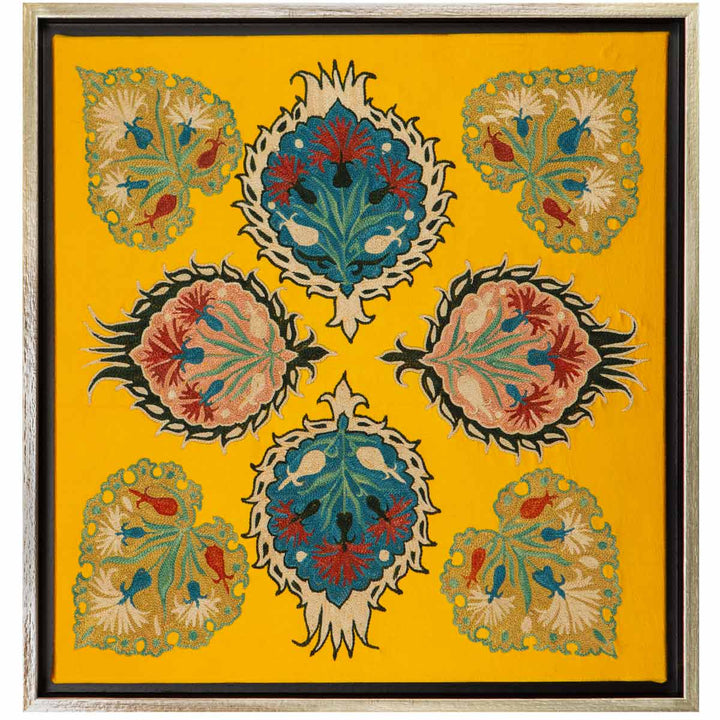 Front view of Mekhann's yellow botanical silk embroidered artwork,  depicting an arrangement of floral and botanical designs that have been hand embroidered onto a silk yellow background, within a metallic frame.