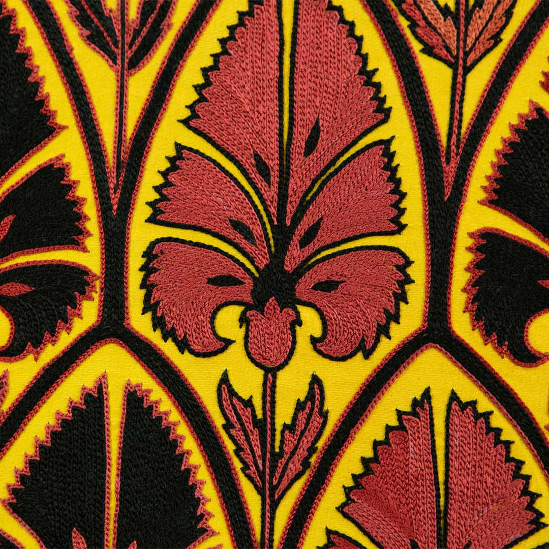 Close up view of Mekhann's yellow silk artwork with black and red embroidered patterns,  focusing on the intricate black and red hand embroidered patterns against the yellow silk background .