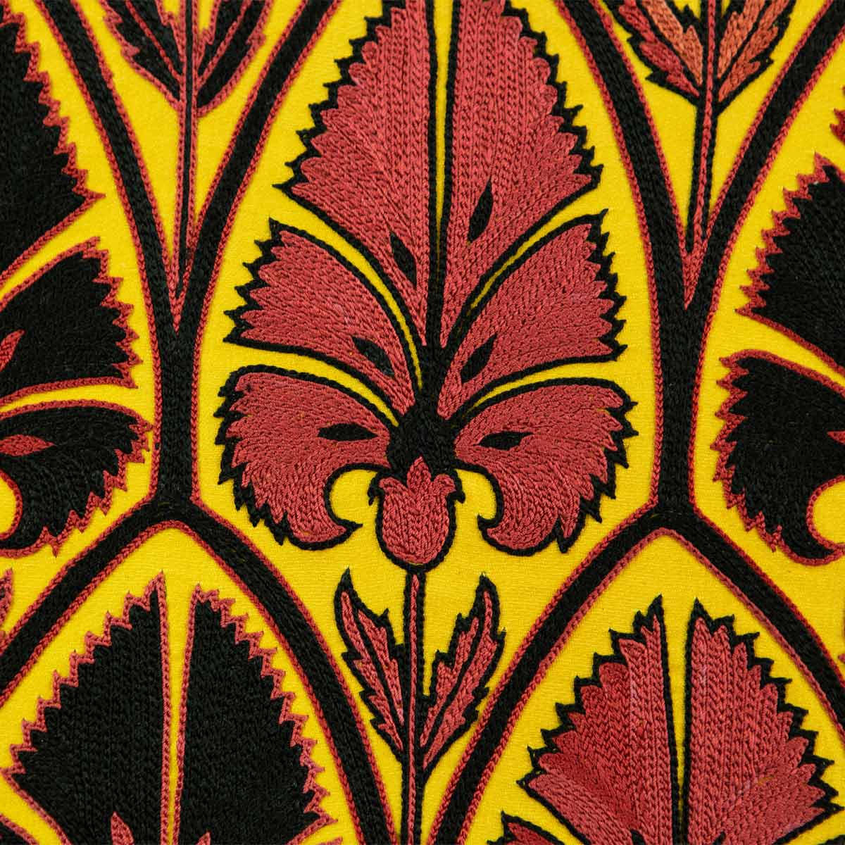 Close up view of Mekhann's yellow silk artwork with black and red embroidered patterns,  focusing on the intricate black and red hand embroidered patterns against the yellow silk background .