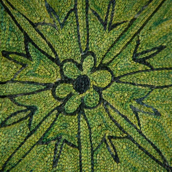Close up view of Mekhann's emerald botanical throw, showing the fine details in the silk hand embroidery, this motif is green with black outline detailing.