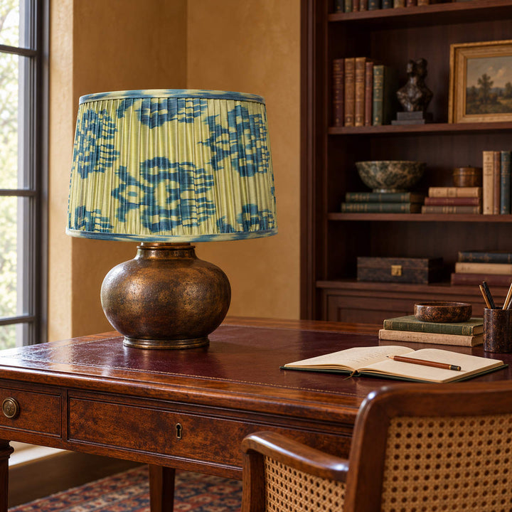 Fleur lampshade styled on a bronze-toned base at a walnut desk beside bookshelves; illustrative study setting.