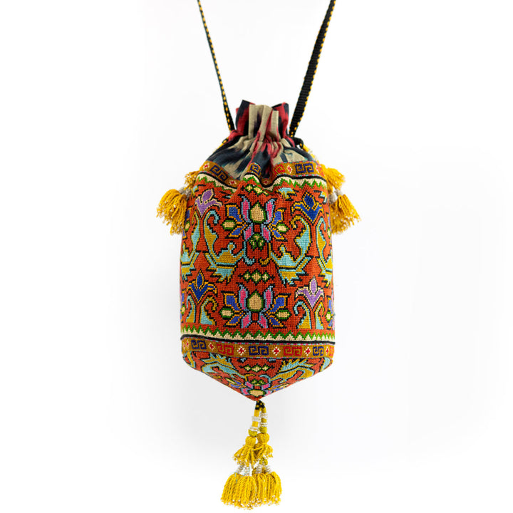 Full view of Mekhann's orange embroidered floral bucket bag, showcasing the unique pattern and handmade tassel embellishments.