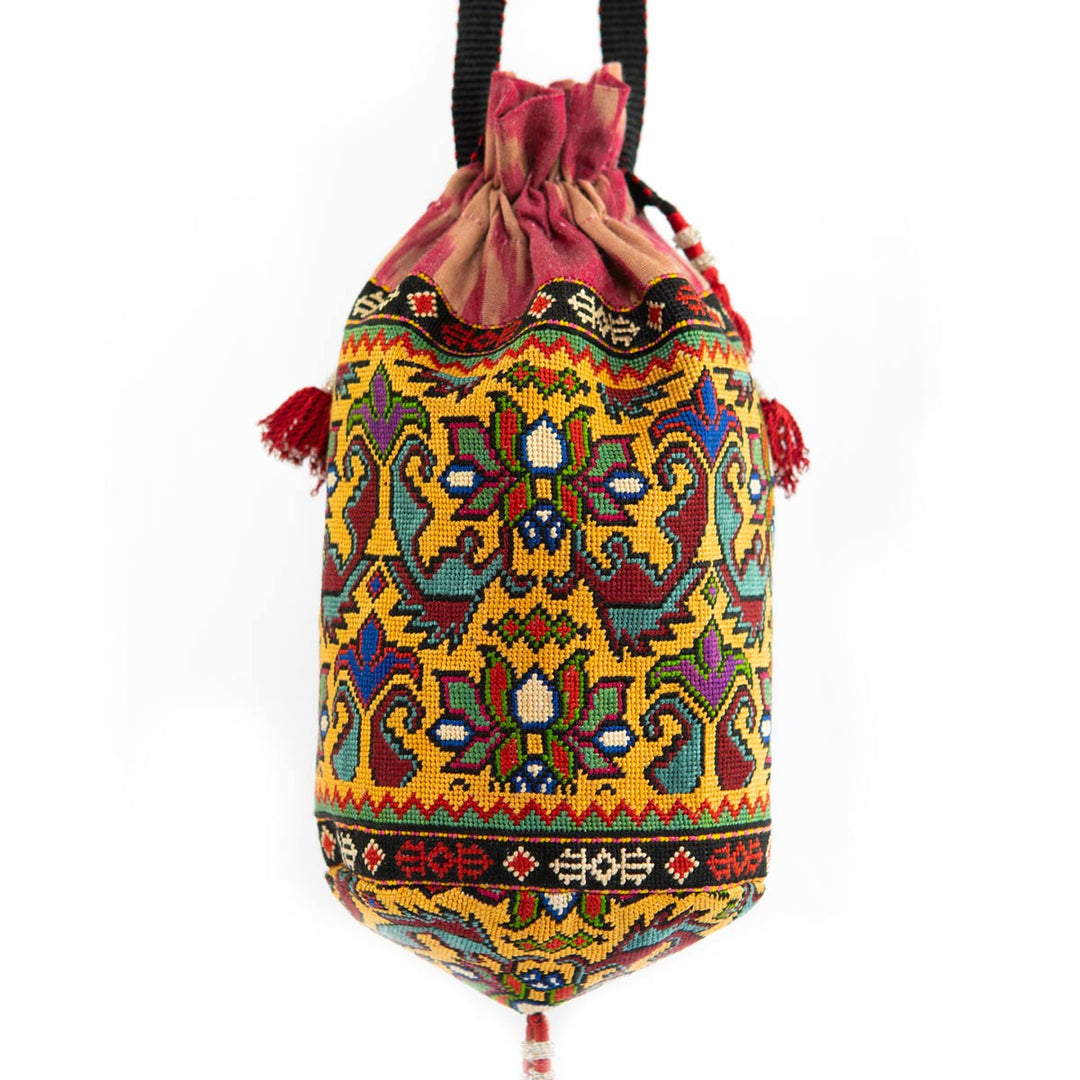 Front view of Mekhann's multicoloured embroidered floral bucket bag,adorned with a vibrant floral pattern and red tassel details.
