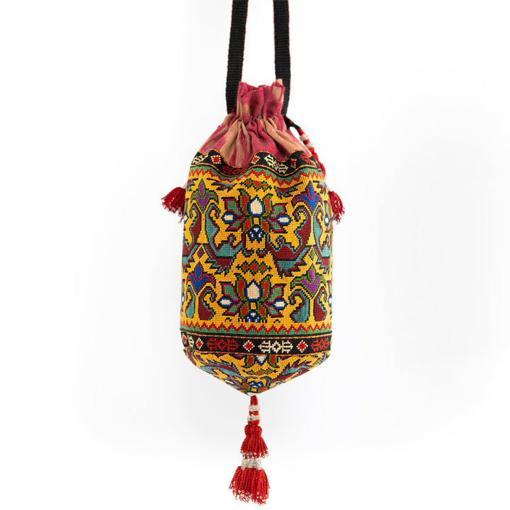 Full view of Mekhann's multicoloured embroidered floral bucket bag, highlighting the unique pattern and handcrafted tassel embellishments. 