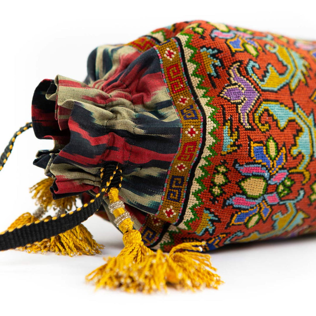Top view of Mekhann's orange embroidered floral bucket bag, displaying the closure feature and the yellow tassels.