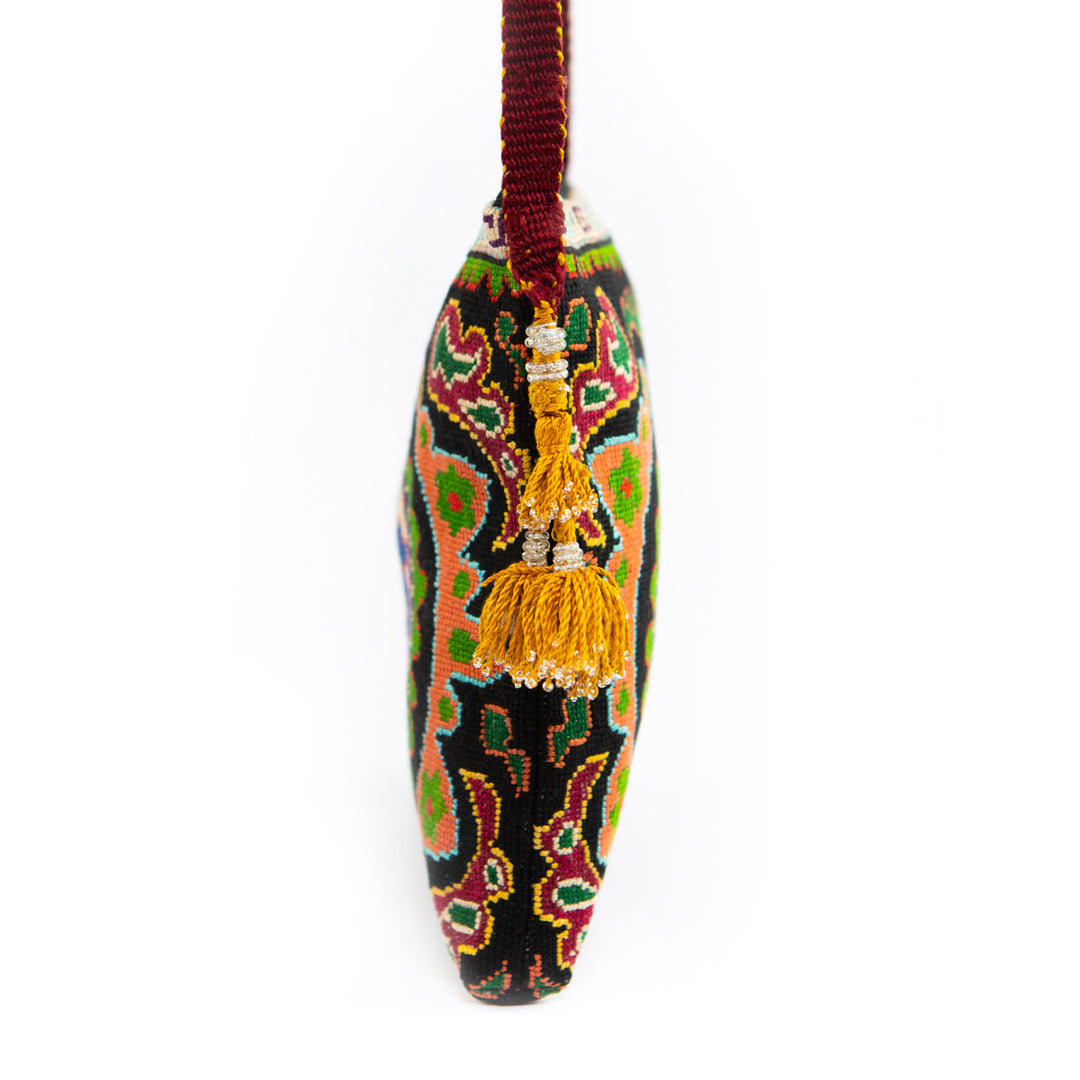 side view of Mekhann's black and multicoloured floral embroidered cross-body, showing the full view of the side yellow tassels.