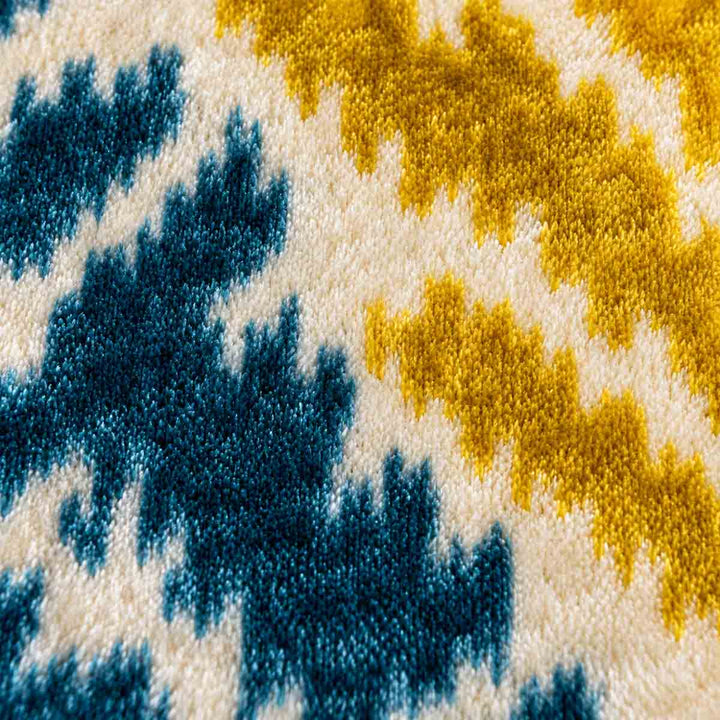 Close-up of teal and gold branching motifs on the Ivory Frond Cushion. 
