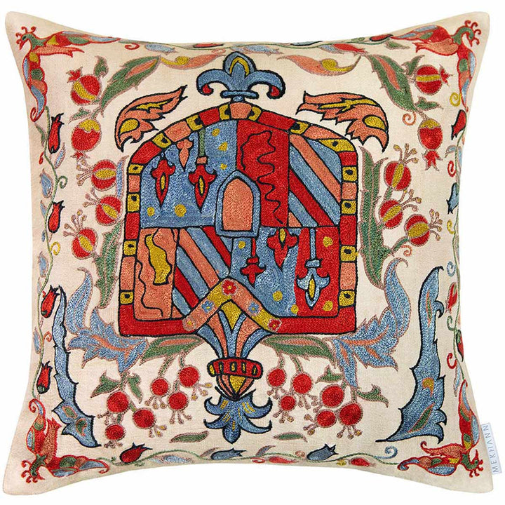 Front view of Mekhann's abstract embroidered cushion, on this cushion we can see a crest shape hand embroidered in bright red, blue, green, with a few black outlines on the details.