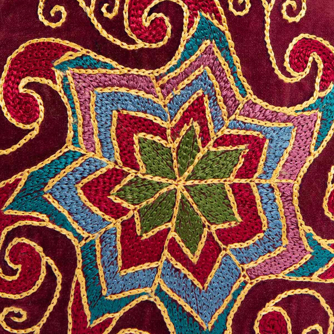 Close up view of Mekhann's geometric dark maroon velvet pouch, bringing you closer to the design intricacies for the embroidered geometric pattern.