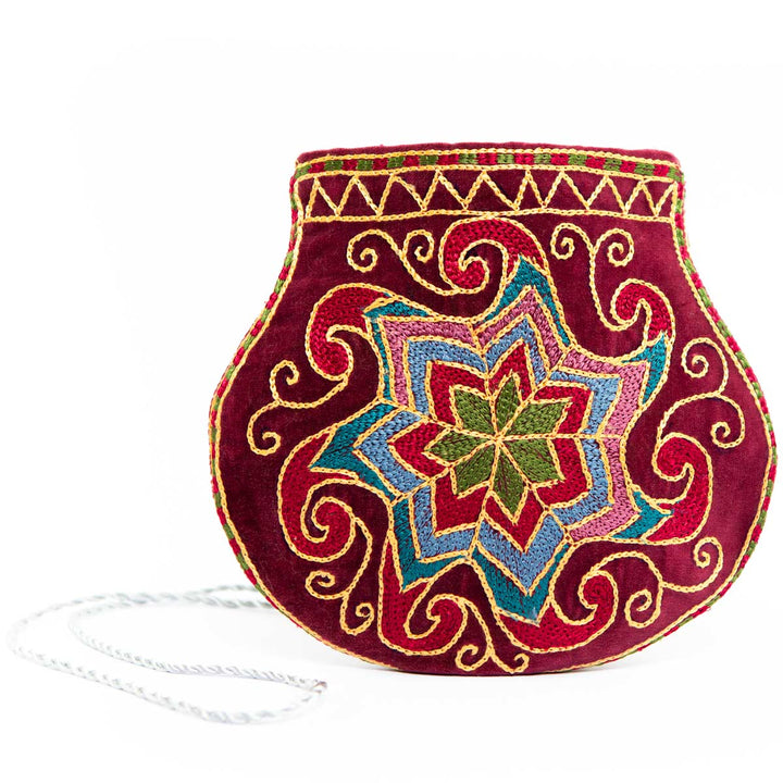 Front view with the strap of Mekhann's geometric dark maroon velvet pouch, showing the ice white strap in contrast with the dark maroon pouch.
