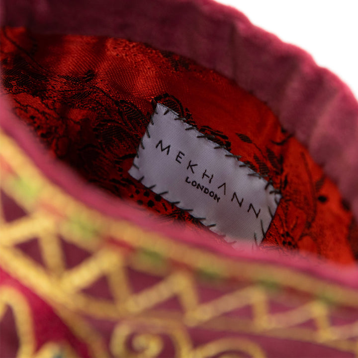 Inside view of Mekhann's geometric dark maroon velvet pouch, showing off a unique red lining to extend the luxury from the outside of the pouch all the way to the inside.