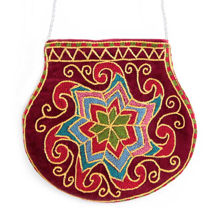 Front view of Mekhann's geometric dark maroon velvet pouch, a unique design created from silk threads in red, blue, pink and green tones.